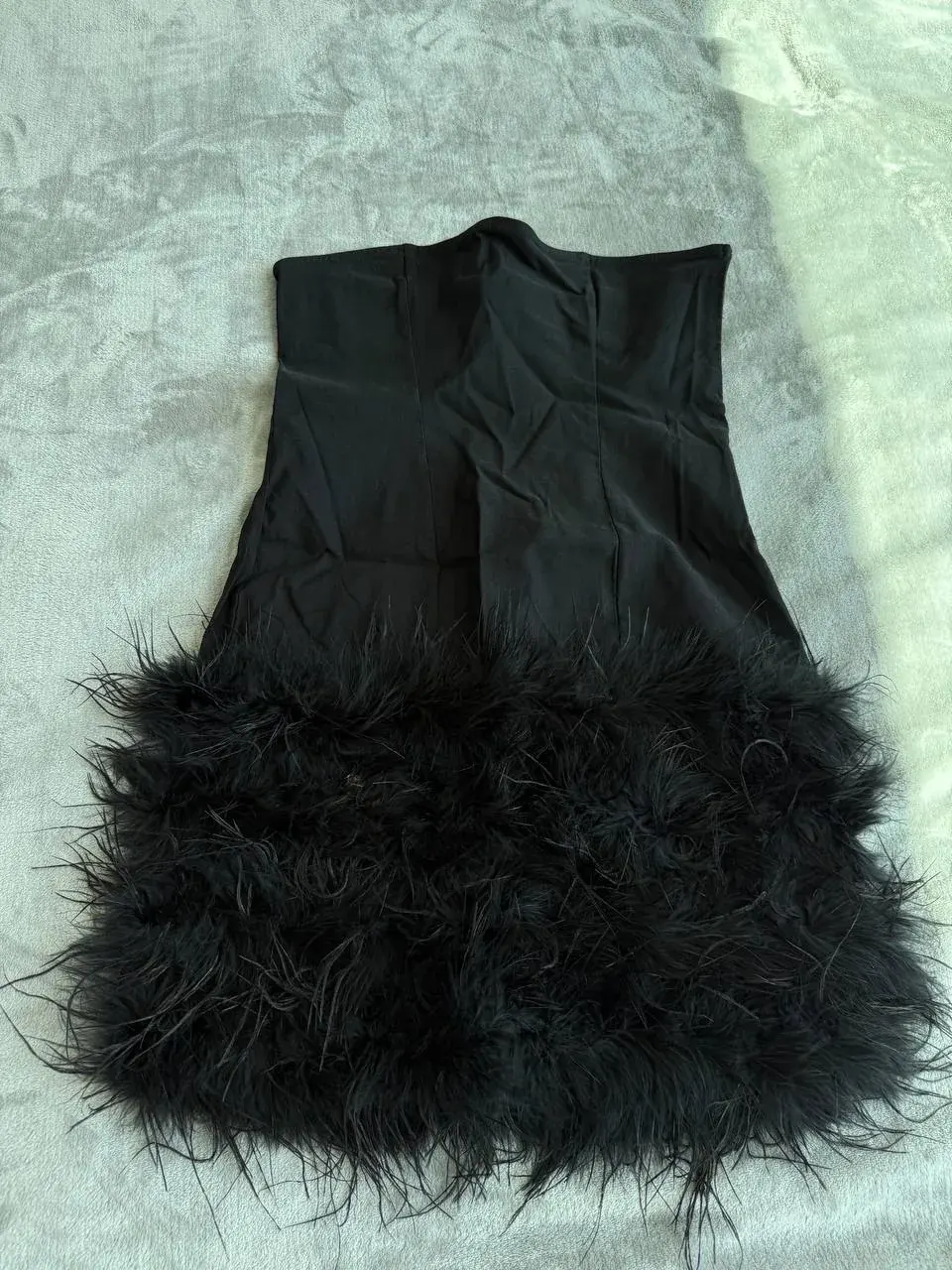 Black sleeveless top with feathered hem laid out as an example of a clothing item to give away or adopt in the UAE reuse app