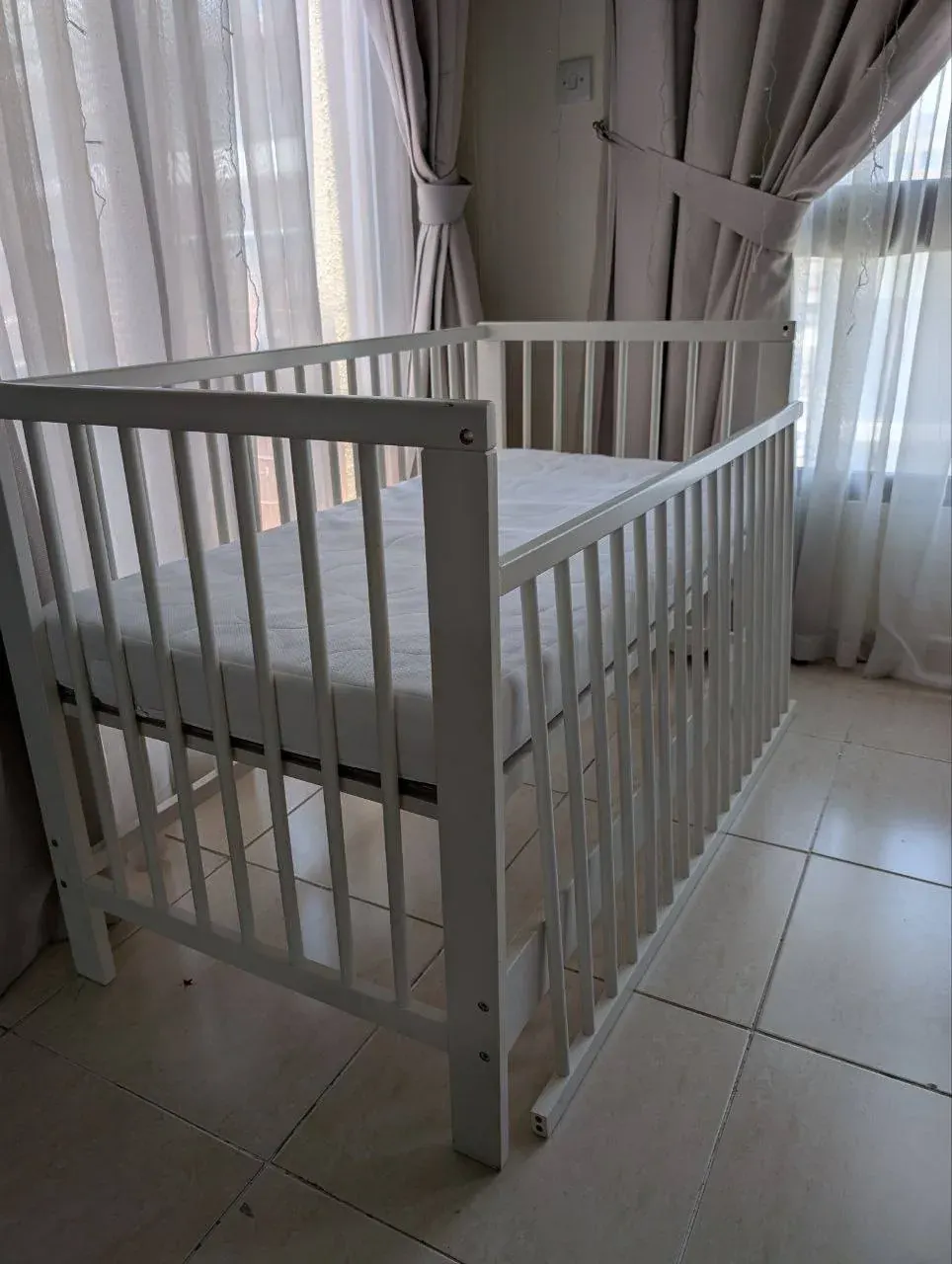White baby cradle in a sunlit room, suggesting gently used baby items that can be shared in Ras Al Khaimah
