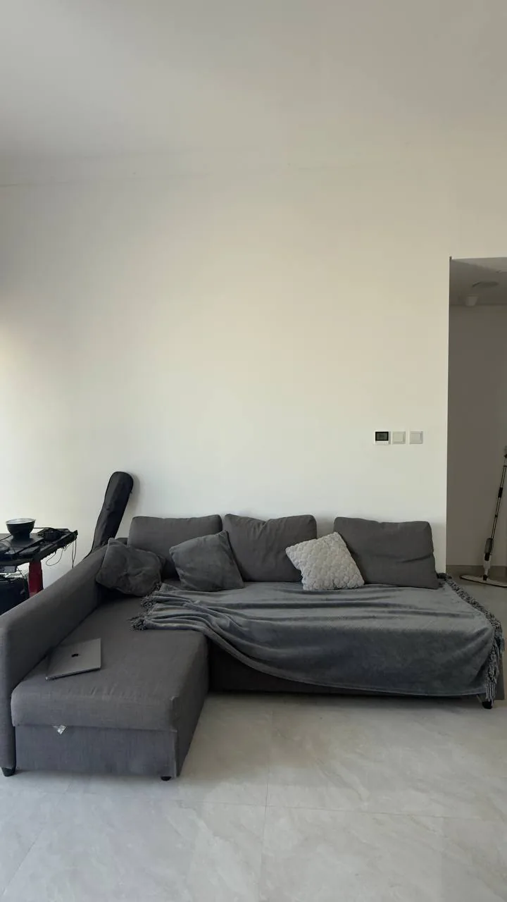 Cozy living room with sectional sofa, blanket and laptop, suggesting pre-loved home items to adopt in the UAE