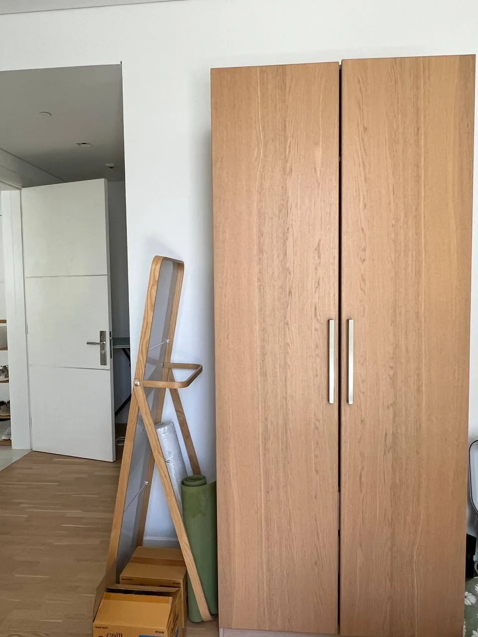 Indoor room with a wooden wardrobe and ladder, suggesting household furniture ready for removal or disposal
