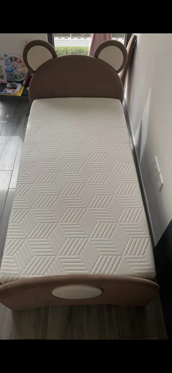 Child-sized bed with rounded headboard and patterned mattress, suitable for giving a second life through reuse in the UAE