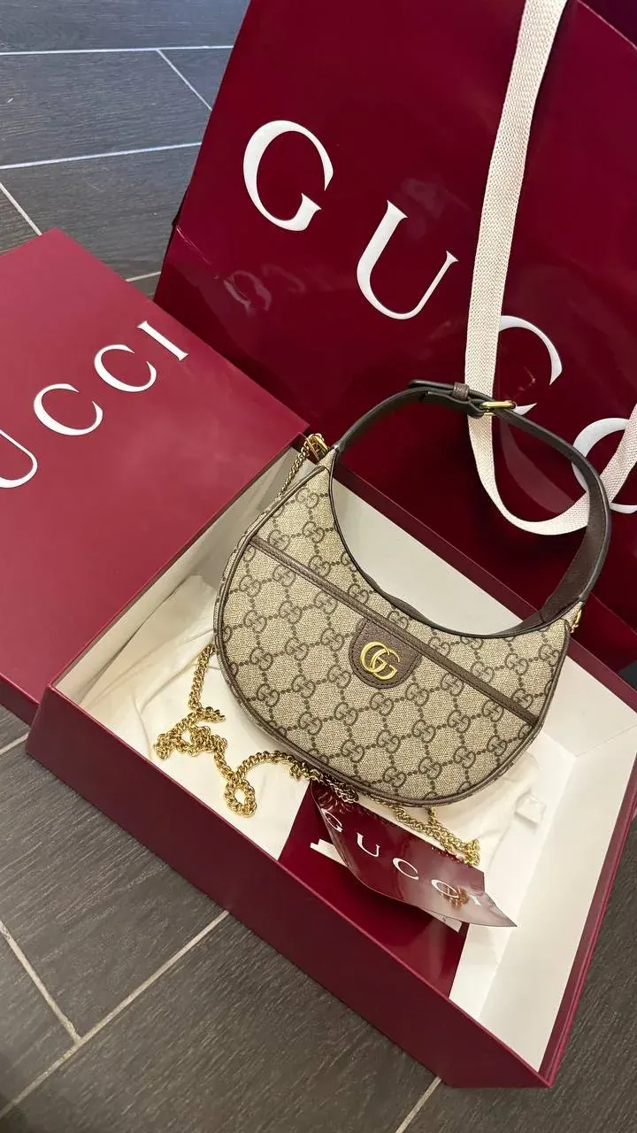 Designer handbag in a Gucci box with shopping bags in the background