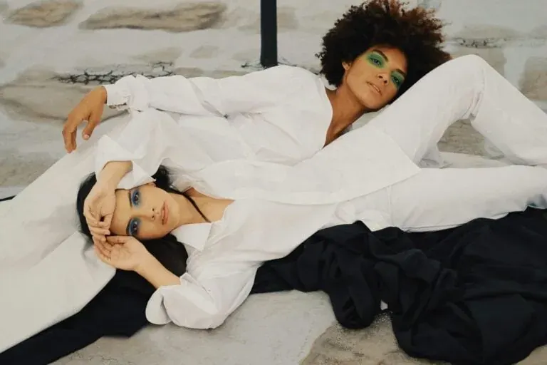 Two women in white outfits posed on the floor for a generic hero image