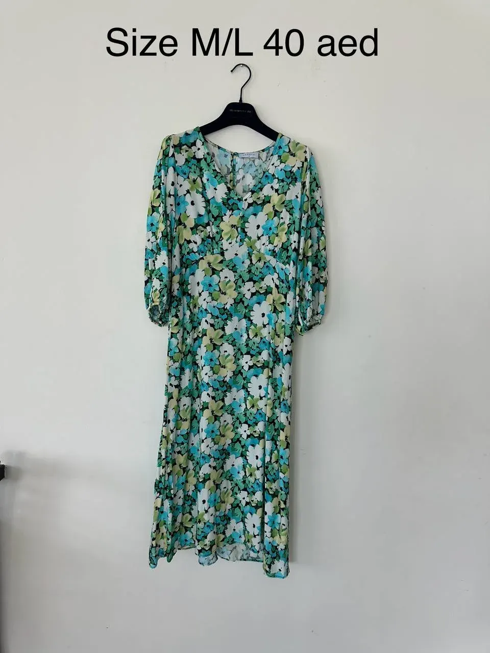 Floral dress on a hanger with visible size M/L and price 40 AED text, useful for describing item size in a uniform handover