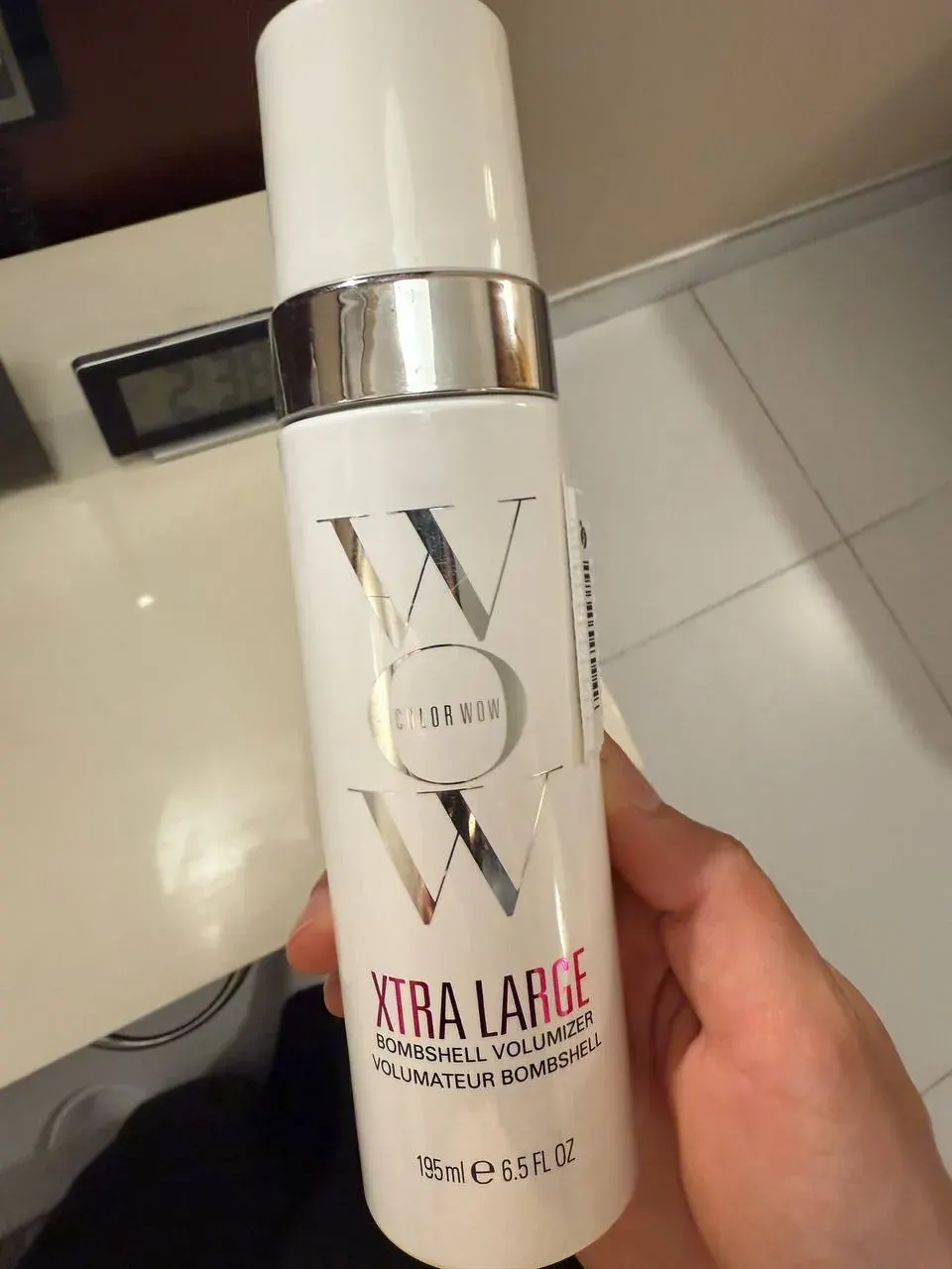 Hand holding a Color Wow Xtra Large Bombshell Volumizer bottle, 195 ml