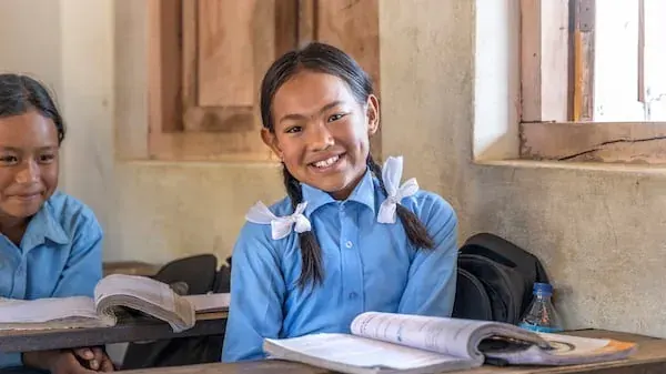 Two schoolgirls in uniform in a classroom, relevant to school clothing reuse in the UAE