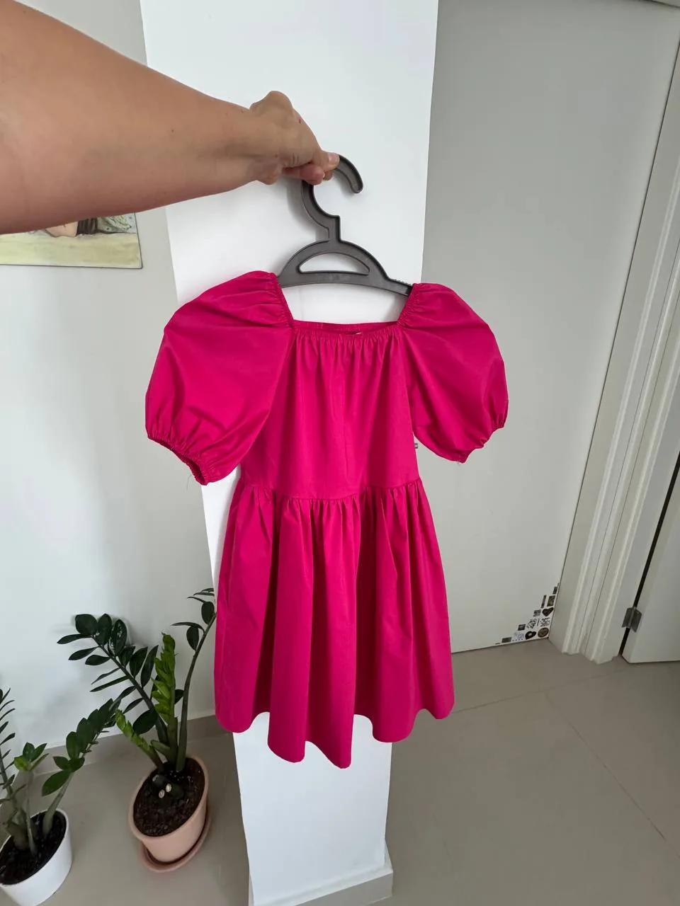 Hand holding a pink dress on a hanger, suggesting passing on pre-loved clothing in a second-hand sharing app context Hand holding a pink dress on a hanger, suggesting passing on pre-loved clothing in a second-hand sharing app context