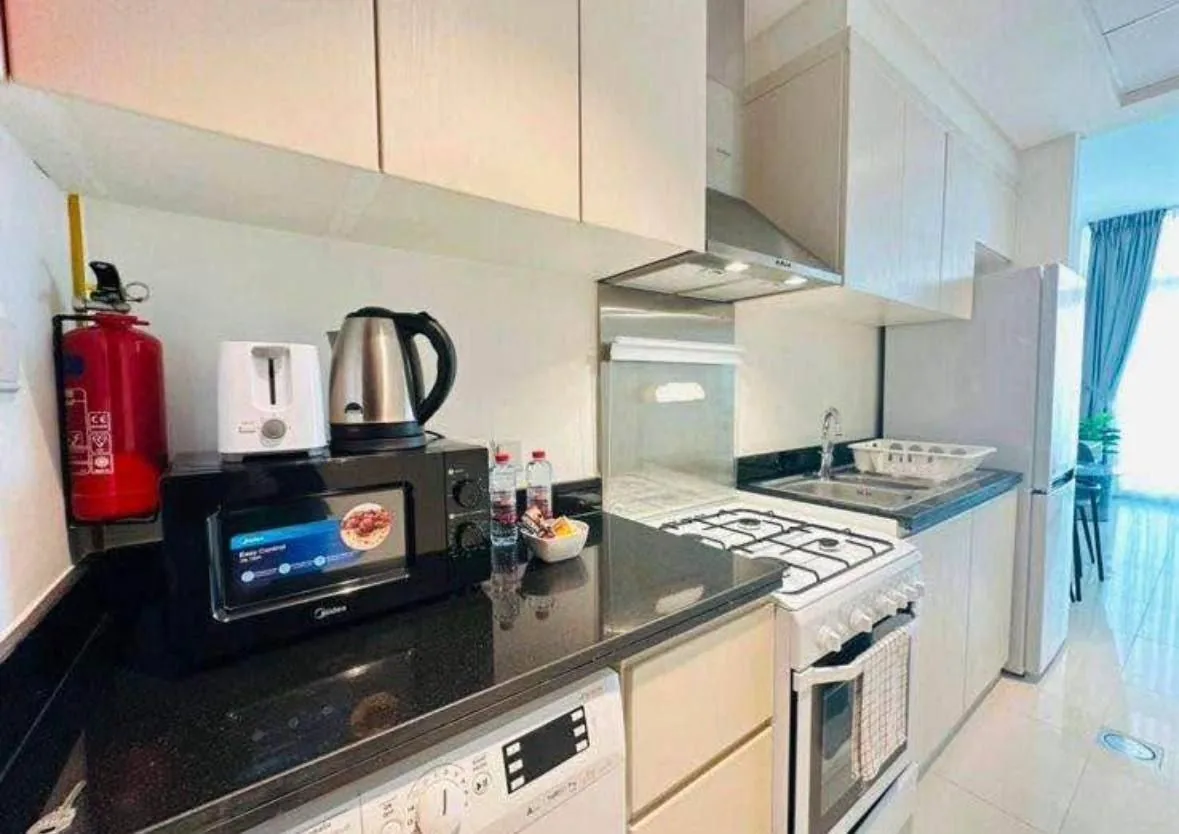 Modern kitchen with sink, gas stove, and small appliances on a black countertop