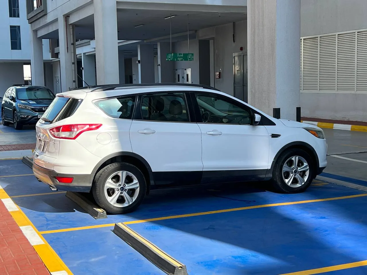 White SUV parked in a marked parking space near a building entrance