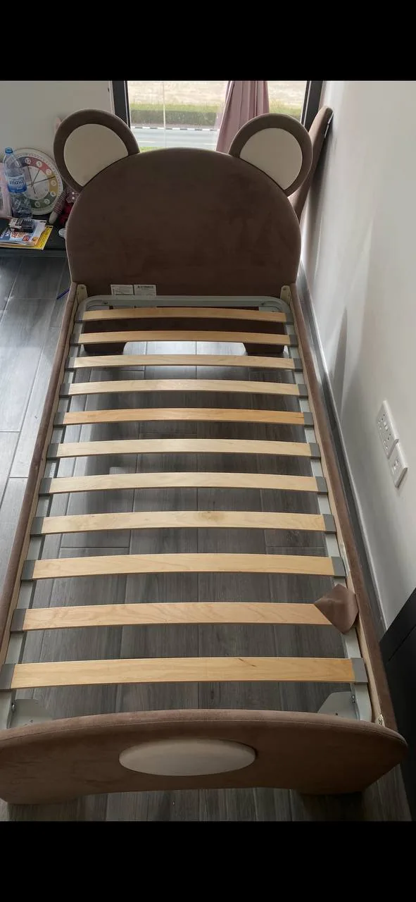 Child-sized bed with bear-ear headboard in a simple room, suggesting a home reset after a life change